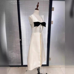White dress with black bow on a mannequin against a glass door background