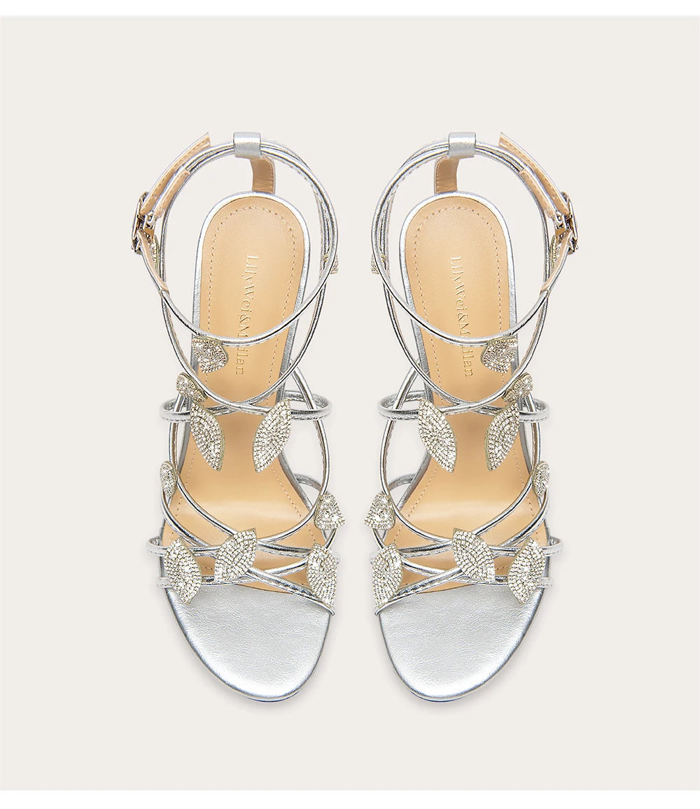 Silver strappy sandals with decorative elements on a light gray background