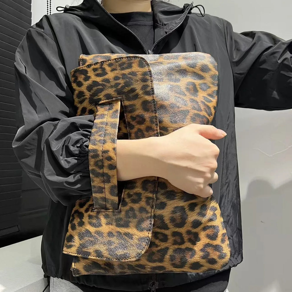 Person holding a leopard print bag with a black jacket