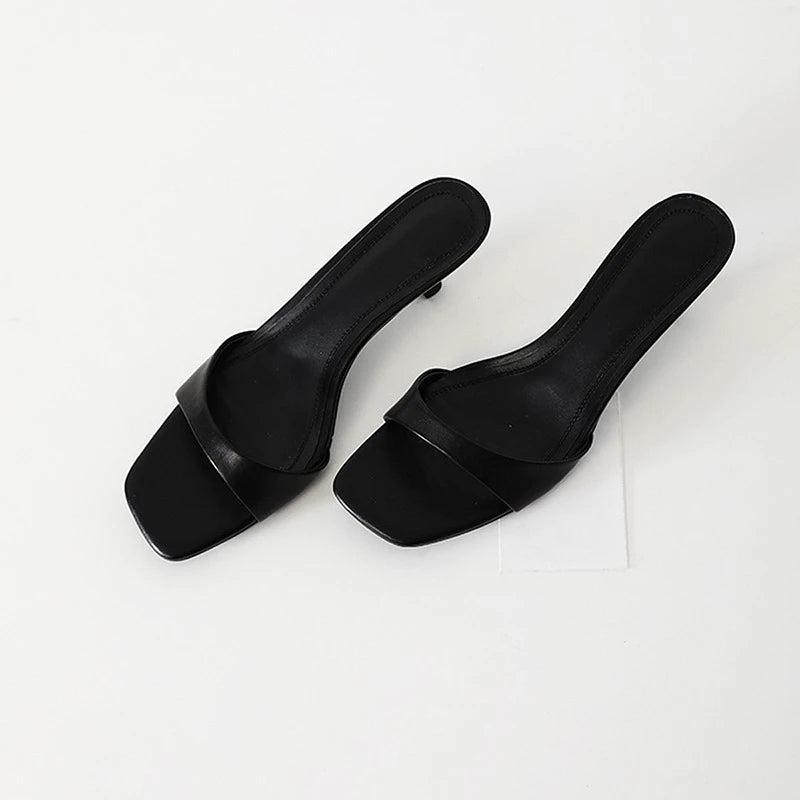 Pair of black square-toe slippers on a white background