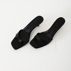 Pair of black square-toe slippers on a white background