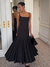 Woman in a black evening gown standing in a room with decorative walls.