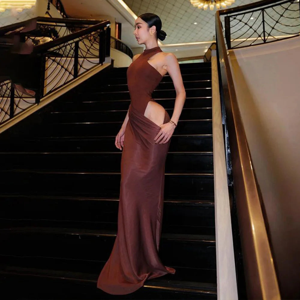 Woman in a long, elegant dress standing on a staircase in an upscale interior setting.