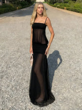 Woman wearing a black dress with sheer panels on a gravel road.