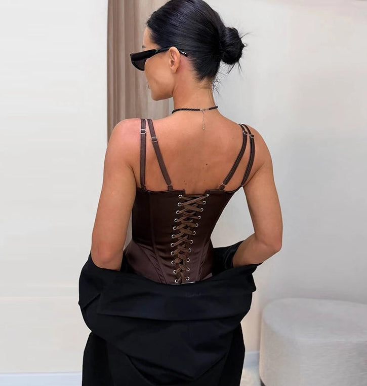 Woman wearing a black corset with lace-up back against a neutral background