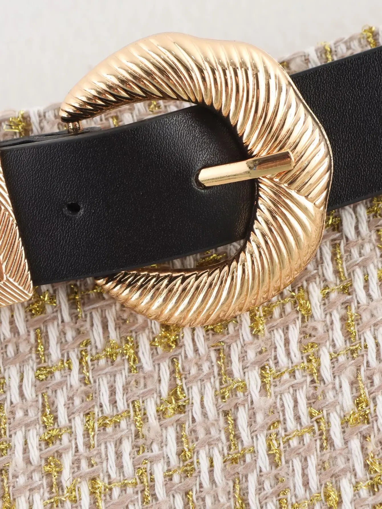 Black belt with a gold buckle on a textured fabric background