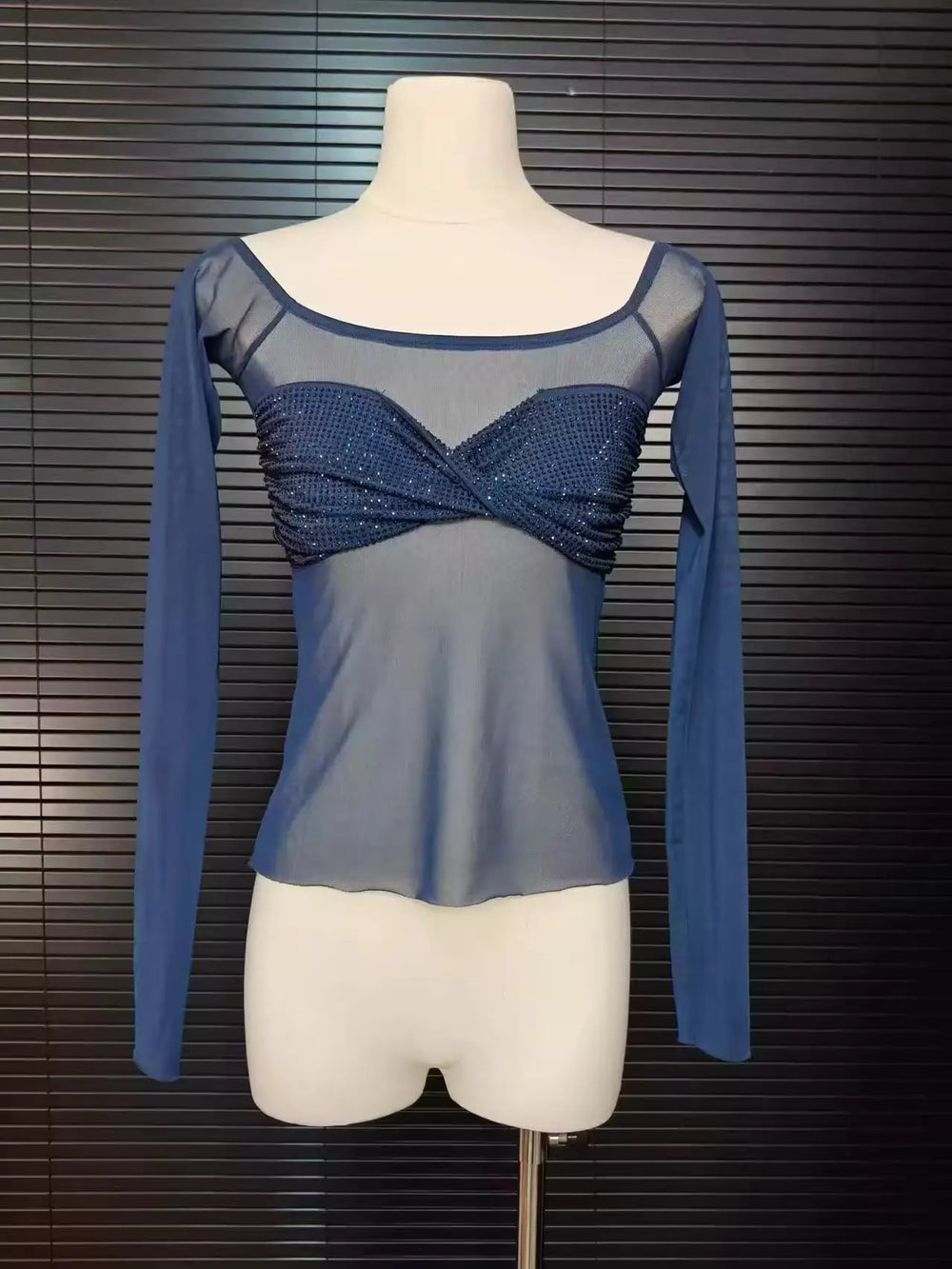 Blue long-sleeve top with a textured pattern on a mannequin against a dark background