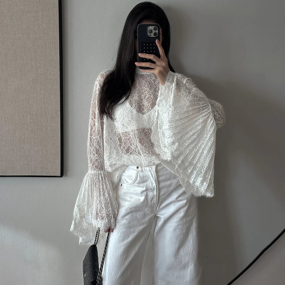 Person wearing a white lace top and white pants taking a mirror selfie.