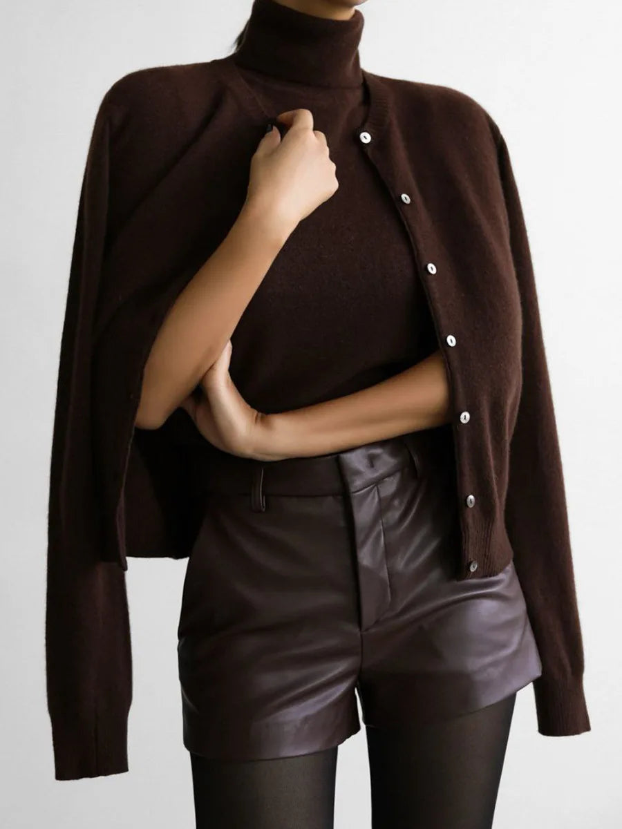 Person wearing a brown poncho over a turtleneck and leather shorts