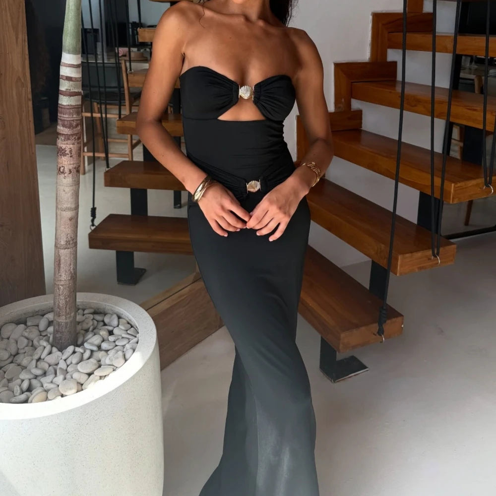 Woman in a black strapless dress standing in a modern indoor setting with wooden stairs.