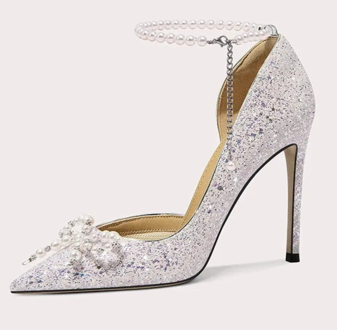 Sparkling high-heeled shoe with pearl details on a light gray background
