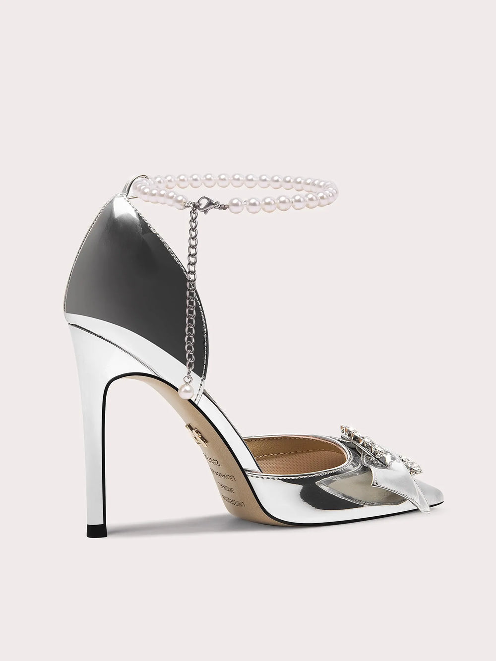 Silver high-heeled shoe with chain detail on a light gray background
