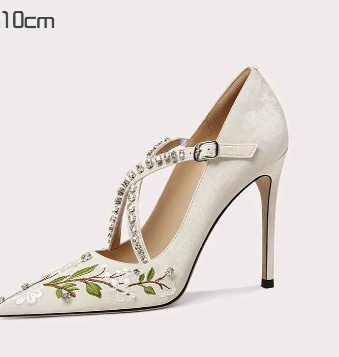 White high-heeled shoe with floral embroidery on a white background
