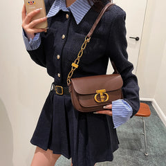 Person wearing a dark blue outfit with a brown handbag in an indoor setting