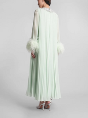 Light green dress with feathered sleeves on a gray background