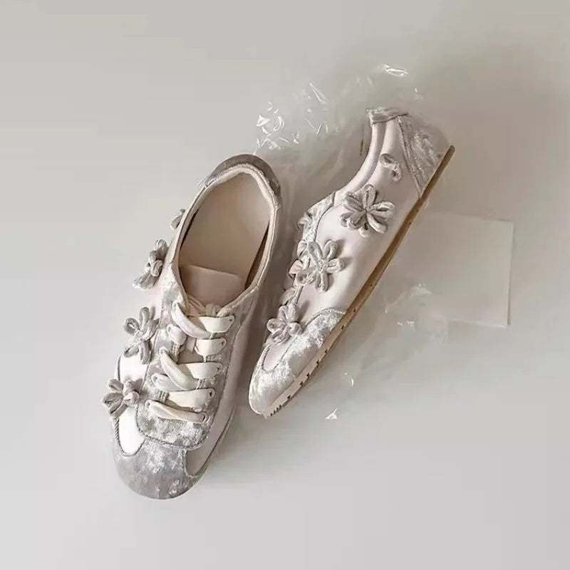 Light grey flannelette sneakers with floral embellishments and lace-up closure.