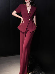 Woman wearing a burgundy suit with gold buttons against a black background