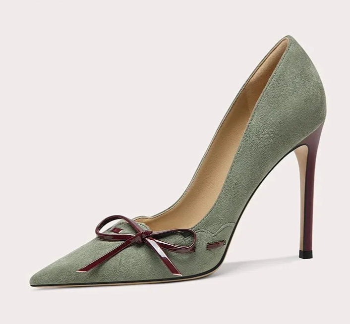 Green high-heeled shoe with a bow on a white background