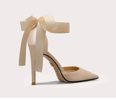 Beige high-heeled shoe with a large bow on a light gray background