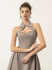 Woman wearing a beige halter neck dress on a white background