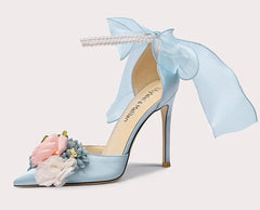 Light blue high-heeled shoe with floral decorations and a bow on a white background