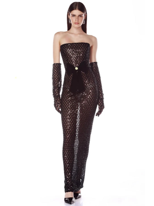 Woman wearing a black sequin jumpsuit with long gloves on a white background