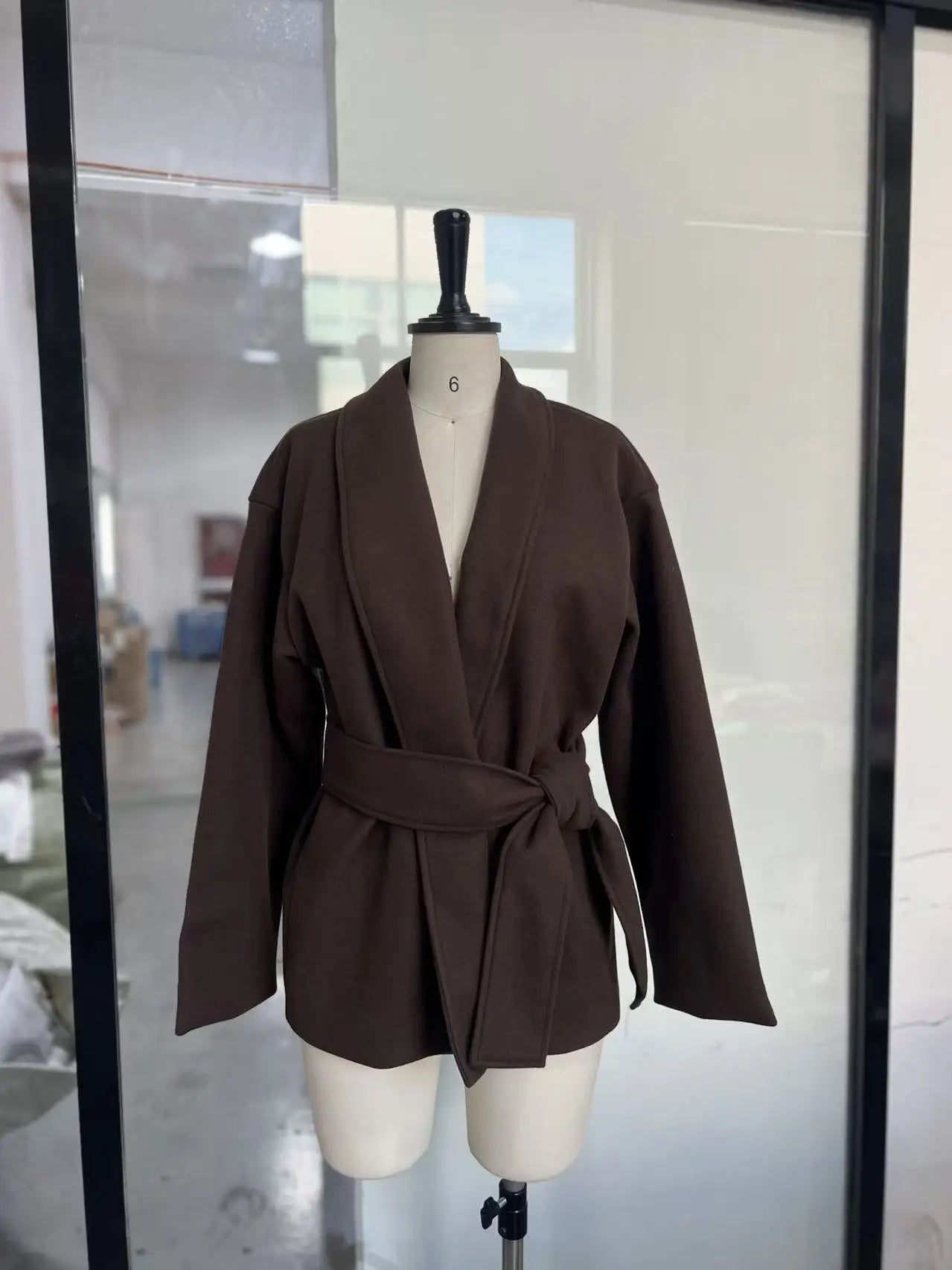 Brown blazer on a mannequin in a room with a mirror.