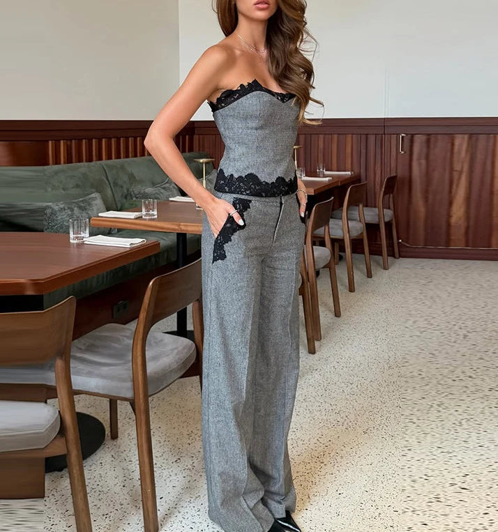 Woman in a gray strapless dress with black lace details standing in a restaurant.