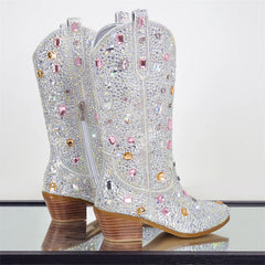 Sparkly cowboy boots with rhinestones on a reflective surface.