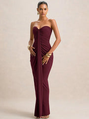 Woman wearing a burgundy strapless gown on a beige background