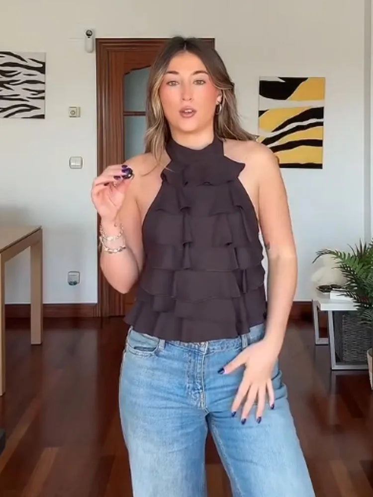 Woman wearing a dark halter top and light blue jeans indoors.