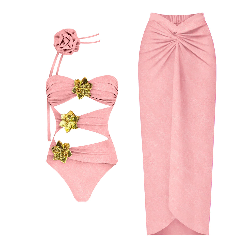 Hot pink one-piece swimsuit with cutouts and gold flower accents, paired with a matching flowing skirt.