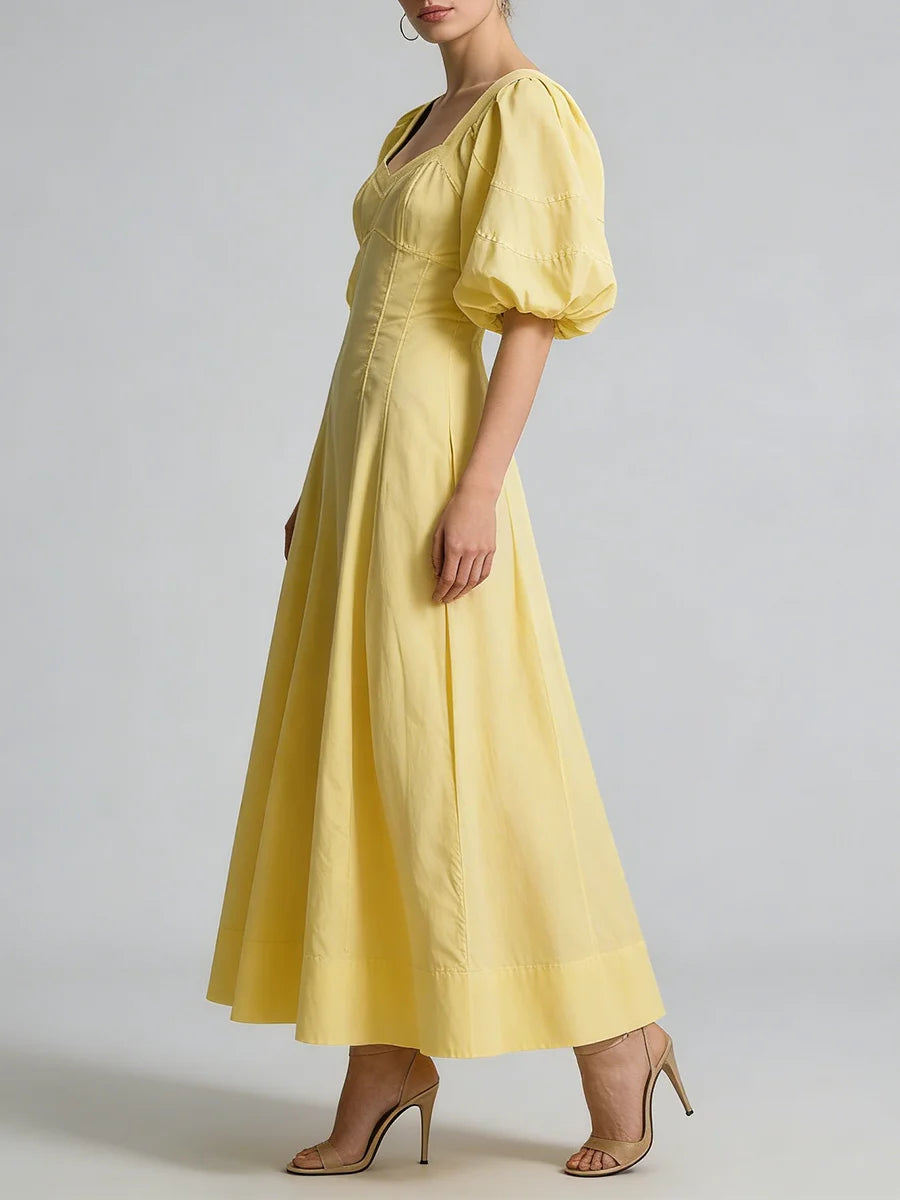 Yellow dress with puff sleeves worn by a model on a plain background