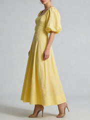 Yellow dress with puff sleeves worn by a model on a plain background
