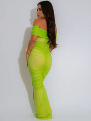 Woman wearing a bright green off-shoulder dress against a white background