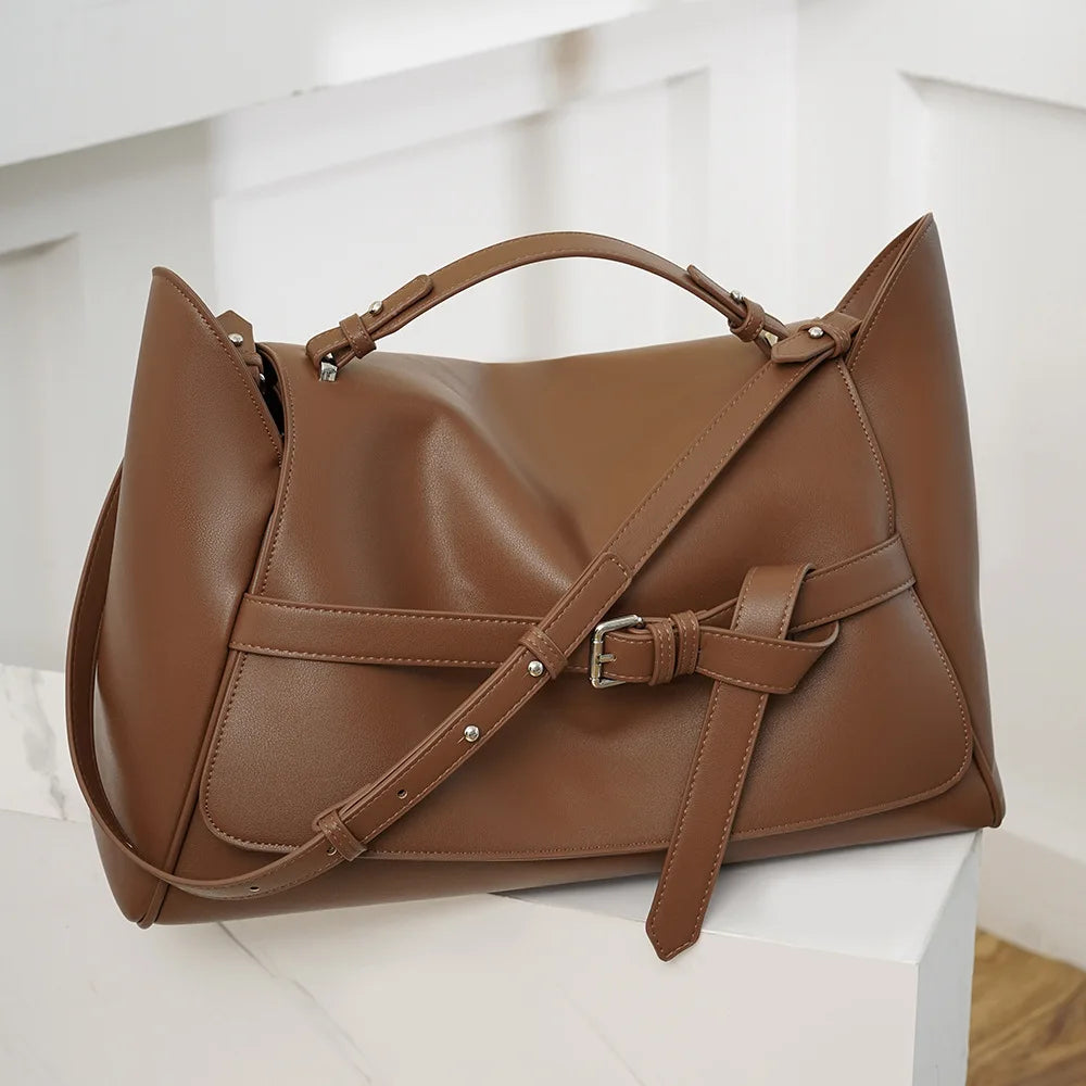 Brown leather handbag on a white surface with a light gray background