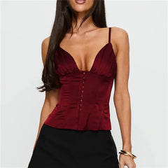 Woman wearing a burgundy top with thin straps on a plain background