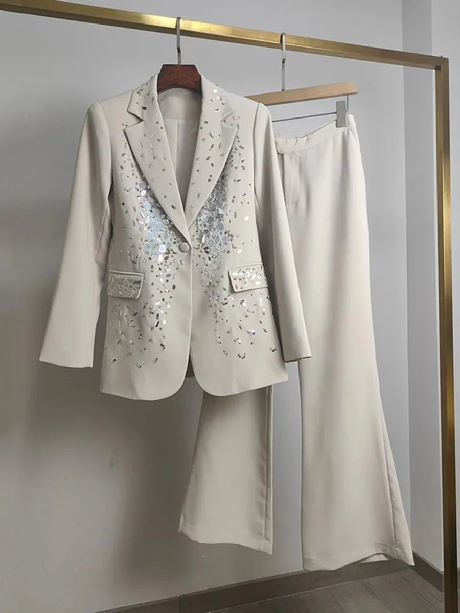 White suit with sequin details on a hanger against a plain background