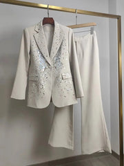 White suit with sequin details on a hanger against a plain background