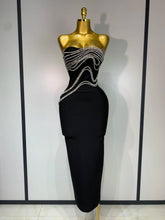Black evening gown with silver embellishments on a mannequin against a neutral background