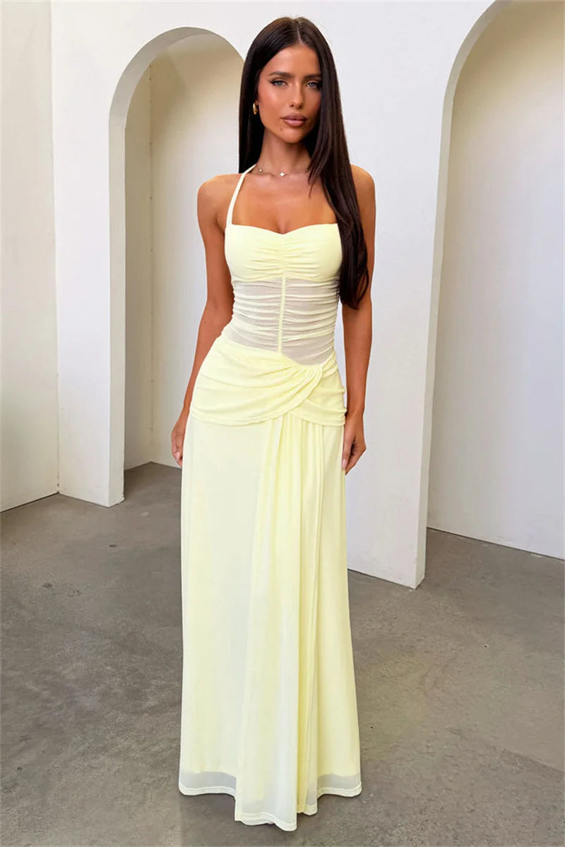 Woman wearing a light yellow dress standing in a minimalistic setting with white arches.