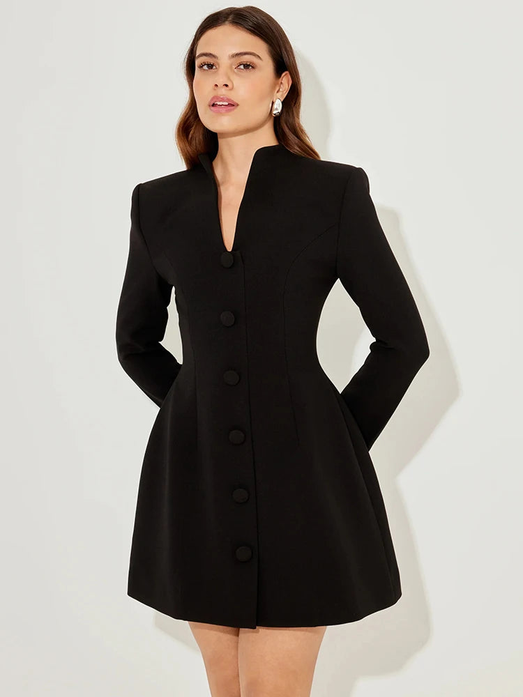 Woman wearing a black coat dress against a white background
