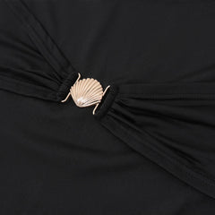 Close-up of a black garment with a gold shell brooch.