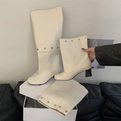 White knee-high boots on a white platform with a neutral background
