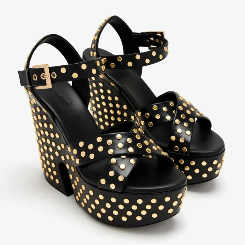Pair of black leather platform wedge sandals with gold studs on a white background