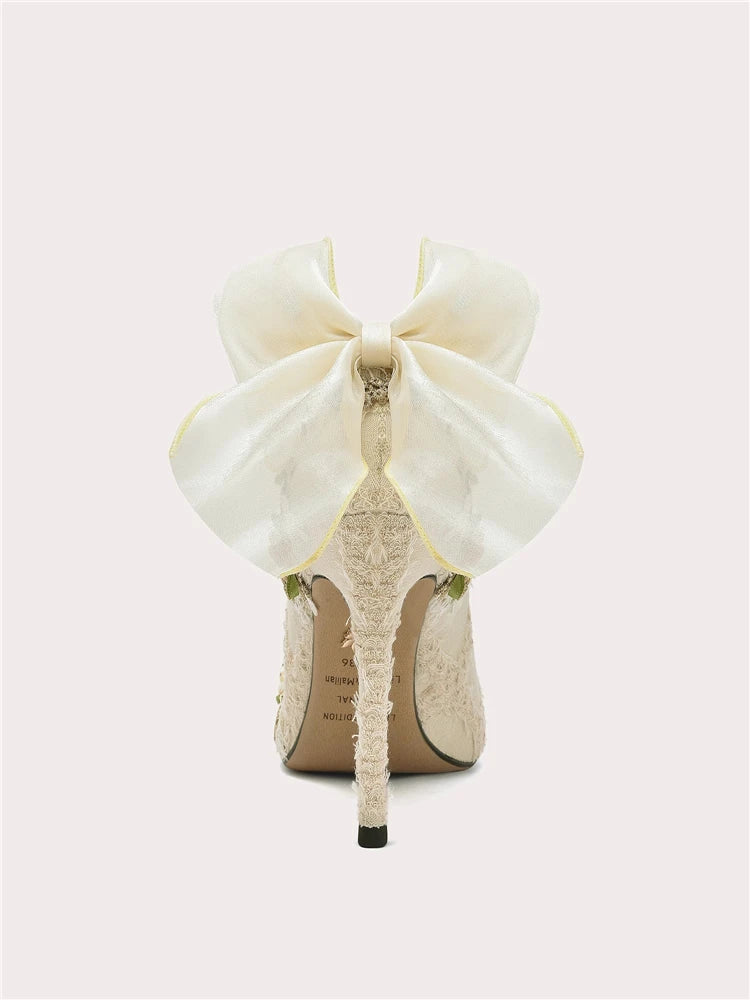 White high-heeled shoe with a large bow on a white background