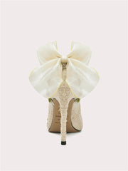 White high-heeled shoe with a large bow on a white background