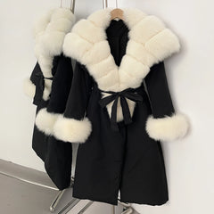 Black coat with white fur trim on a hanger against a white background