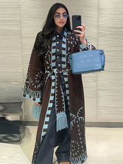 Woman taking a selfie wearing a patterned coat and holding a blue handbag.