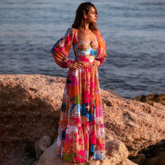 Model posing in a long sleeve printed one piece swimsuit and skirt beachwear set.